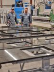 Werkstatt mut mehreren Küchenarbeitsplatten, Massenfertigung. und 2 Arbetern im Hintergrund.